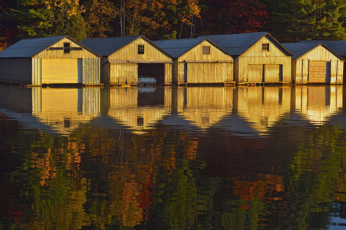 Boat houses reflected in the waters of Penage/Panache Lake at the Penage/Panache Lake marina, Greater Sudbury (Penage Lake area), Ontario, Canada.