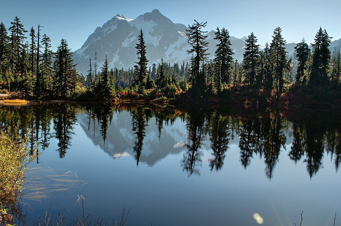This landscape photo is of Picture Lake at Heather Meadows on Mt  Baker Washington in autumn  Breath taking mountain is reflected off the water of the lake and fall foliage surrounds the edges  Located in peaceful Baker National Forest in Whatcom County, 