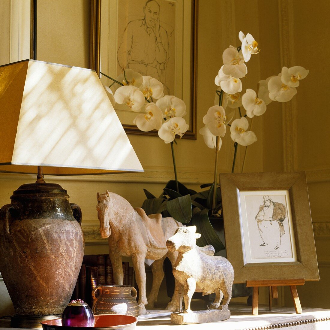 A table lamp with a white shade and stone animal figures on a shelf