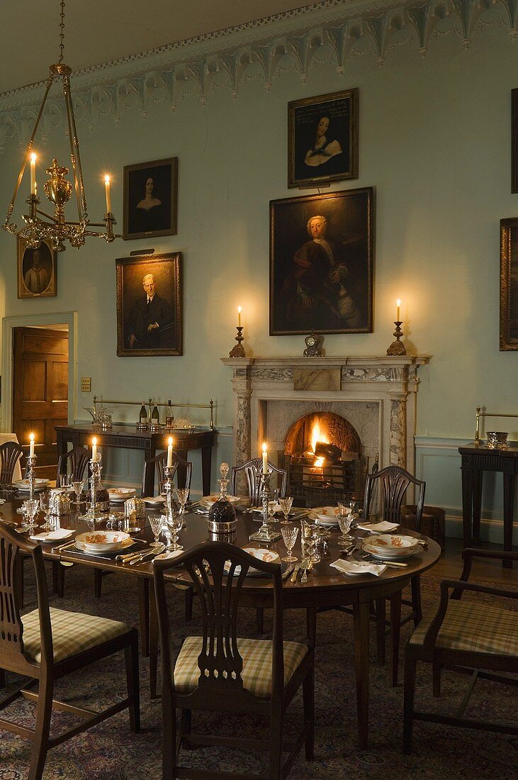 A Baroque room in a castle with a fireplace and a festively laid, candlelit dining table