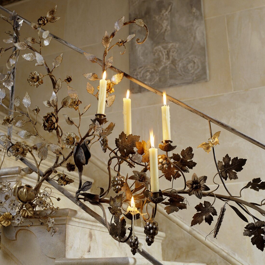 Burning candles in a metal banister featuring a floral design and candle holders