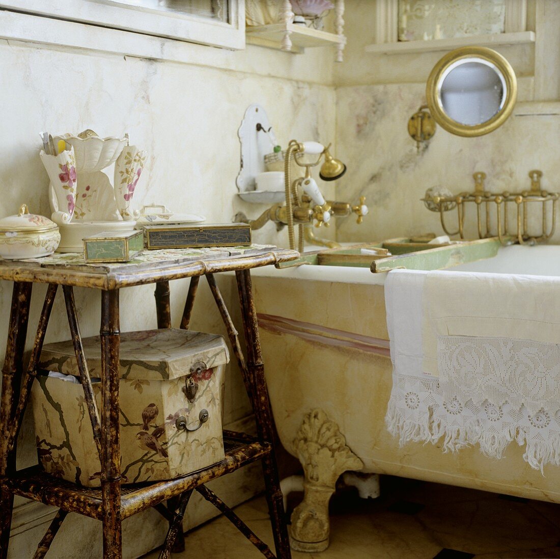 Bathing utensils on a wicker side table next to an antique bathtub with feet and brass taps
