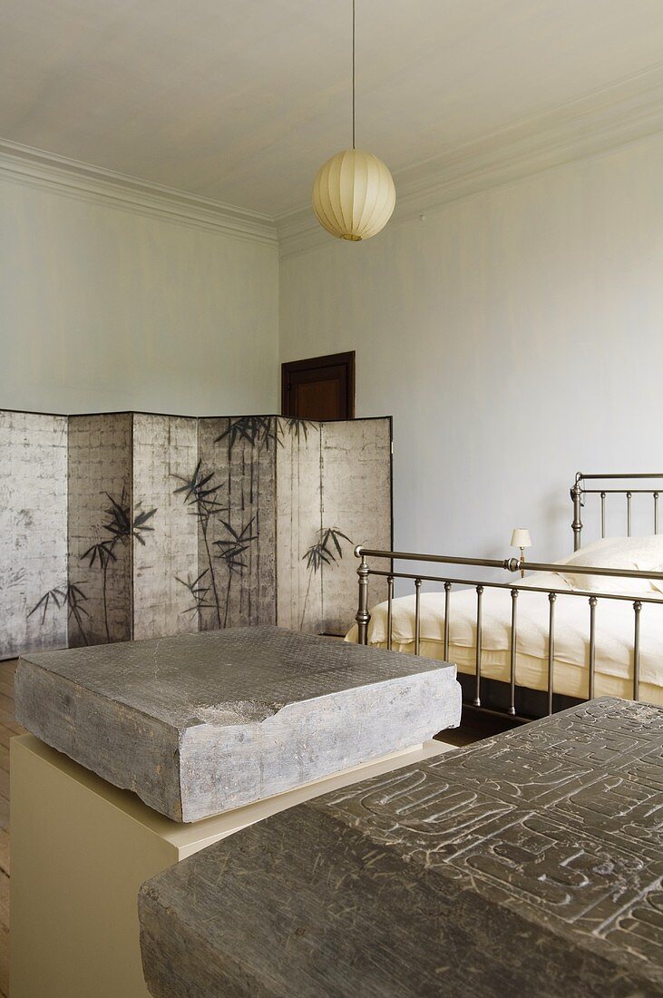 Art in a bedroom - engraved stones on pedestals at the foot of a stainless steel bed
