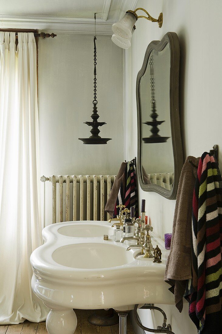 An antique, free-standing wash basin with two sinks and a mirror