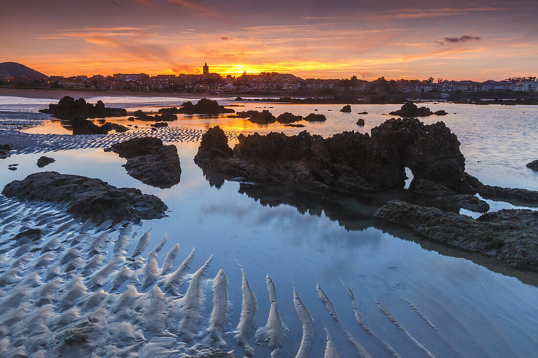 Rocky beach and village at dusk. Trengandin beach. Noja, Cantabria. Spain, Europe.