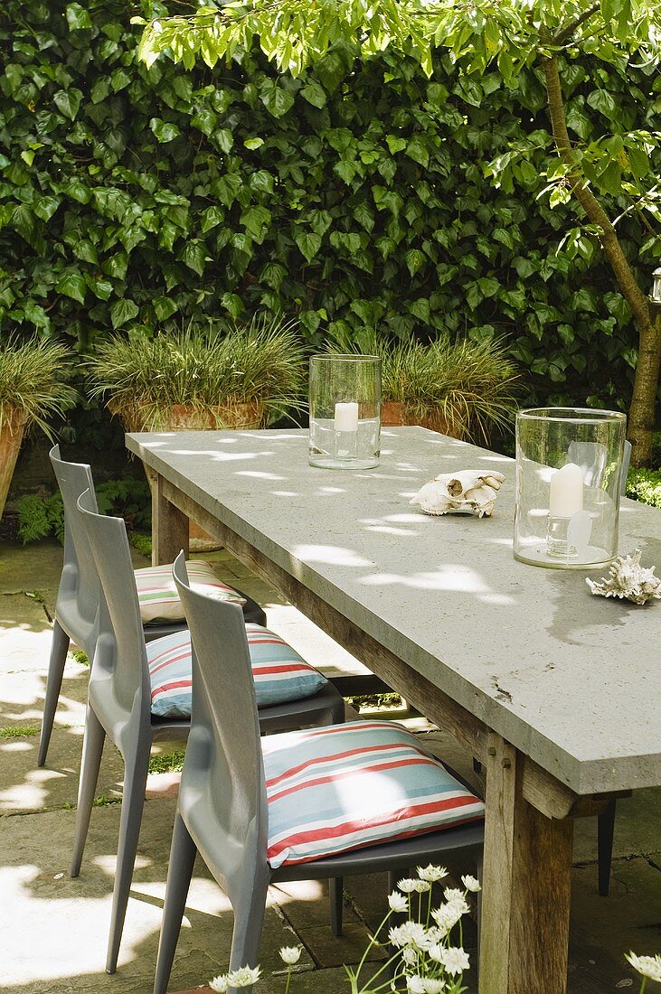 Grey plastic chairs with cushions set around a simple wooden table on a terrace