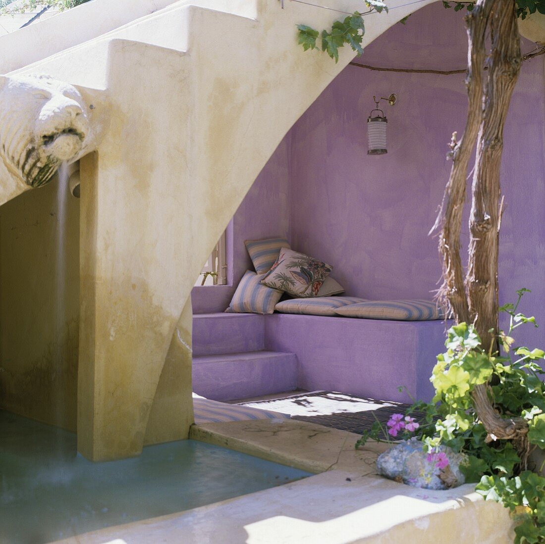 Mediterranean courtyard with a stone flight of steps and a lilac painted, upholstered niche