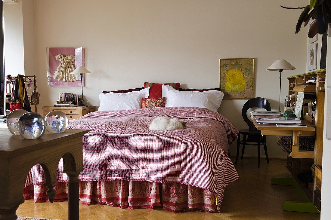 A bedroom with a pink throw on a double bed and a davenport against a wall
