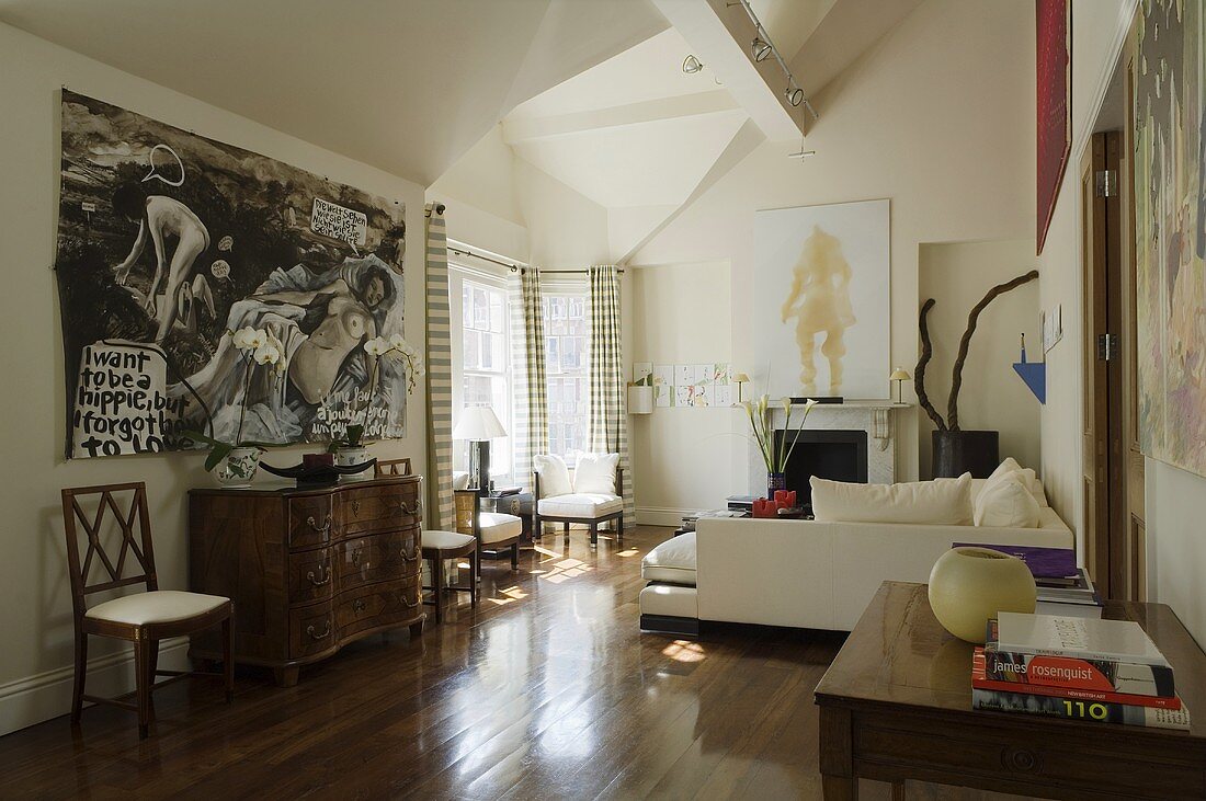 A mixture of styles in a living room with walnut parquet - an antique chest of drawers and a white, modern-style sofa