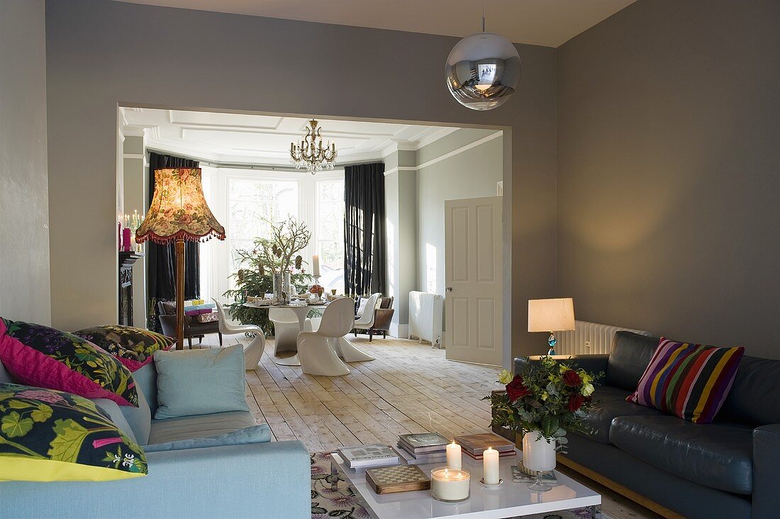 A minimalistic living room with sofas against grey walls and a view into an open-plan dining room