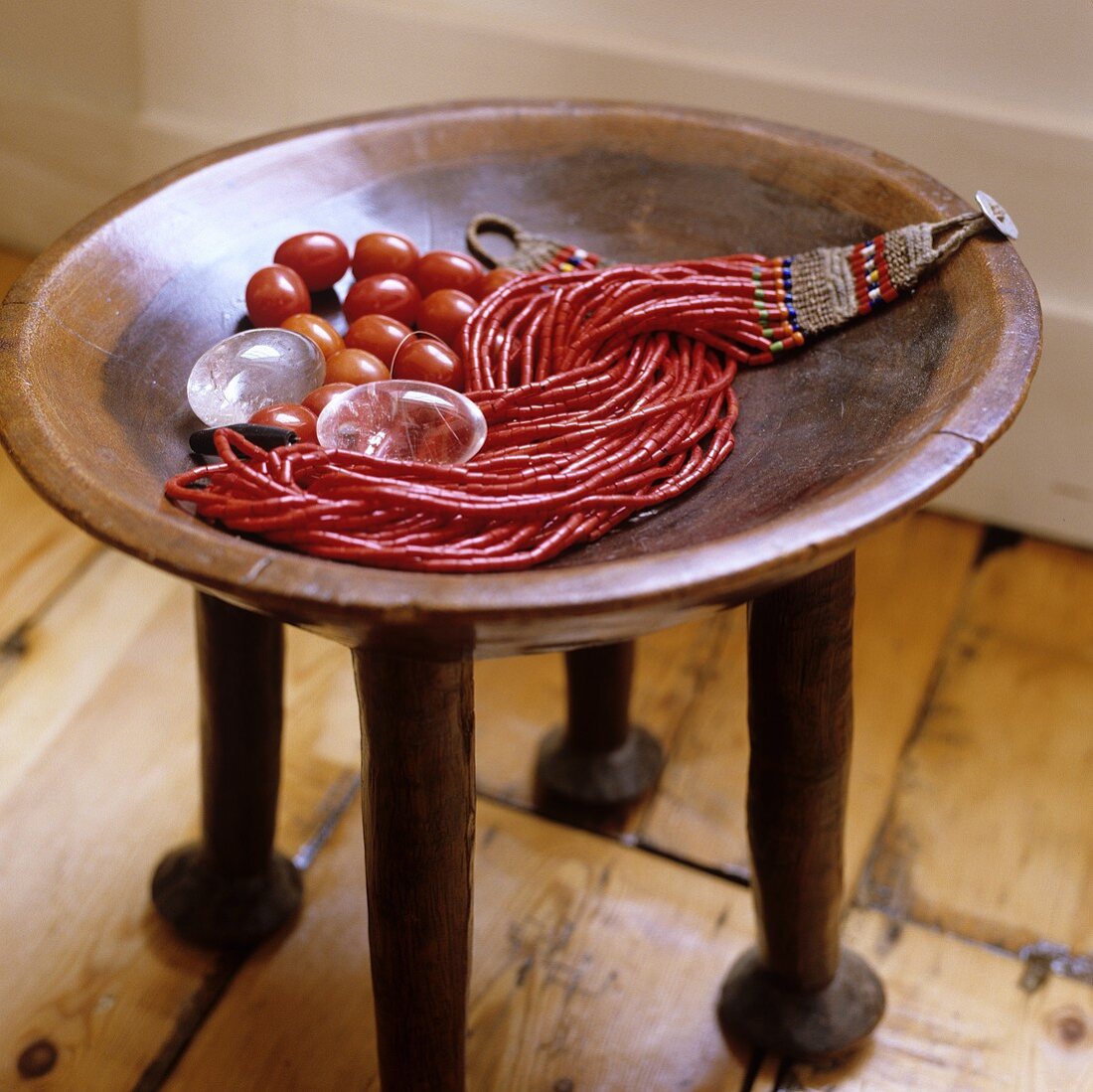 A red coral necklace on an African occasional table