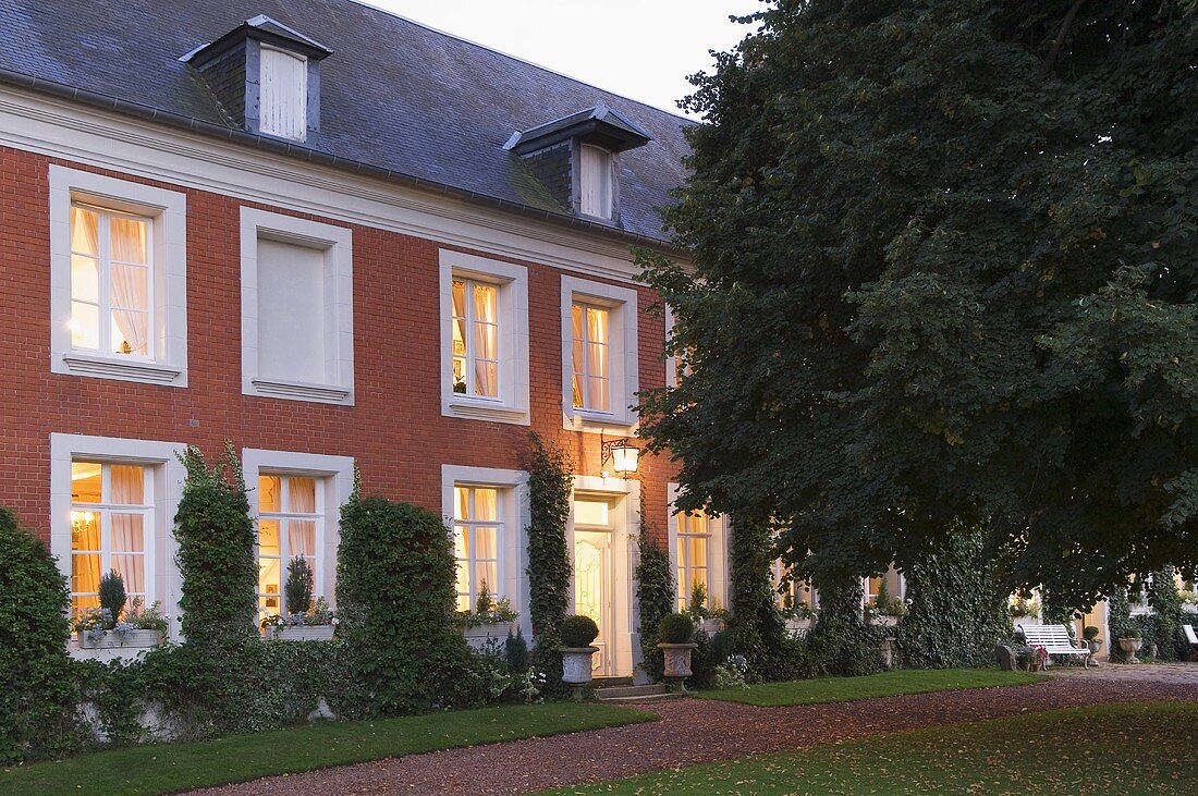 Landhaus mit weissen Fenstern und Ziegelfassade in Abendstimmung