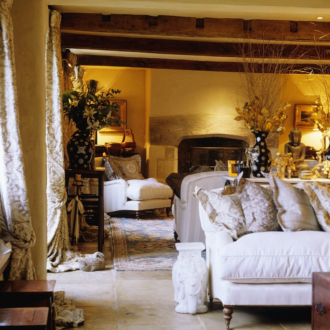 Warm artificial lighting in a country-style living room with a white sofa under a rustic wooden beamed ceiling