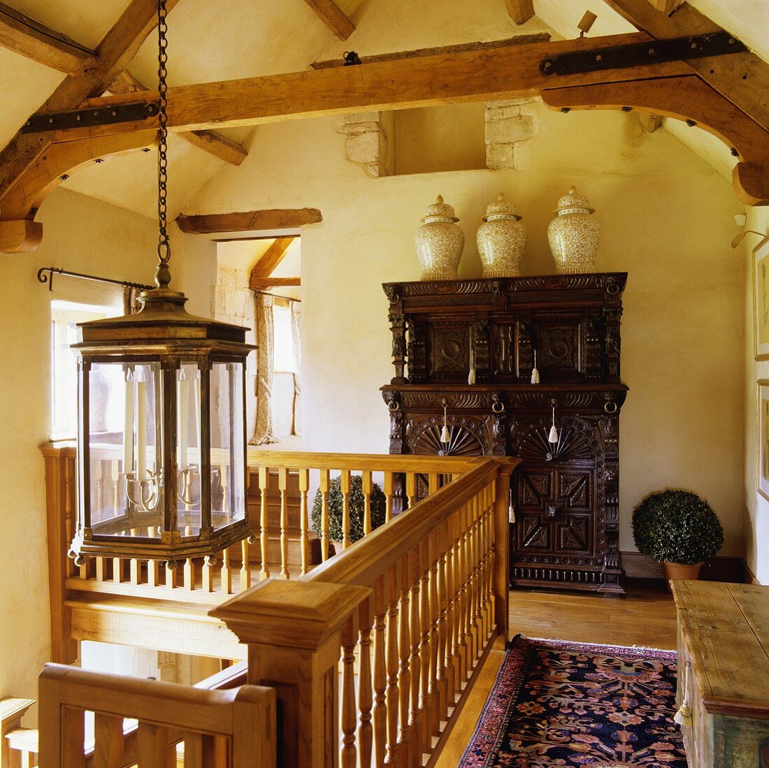 Vases on top of a wooden Oriental cupboard in a gallery with wooden banisters in a rustic attic