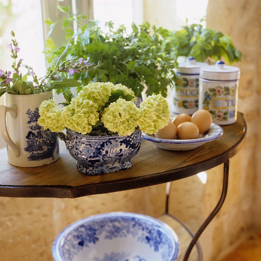 Bunches of herbs and flowers in porcelain jars on a side table