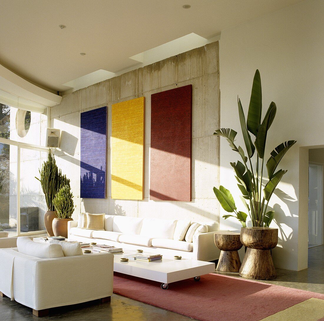 A living room in a Mediterranean house - designer furniture in front of a concrete wall with solid colour abstract artwork
