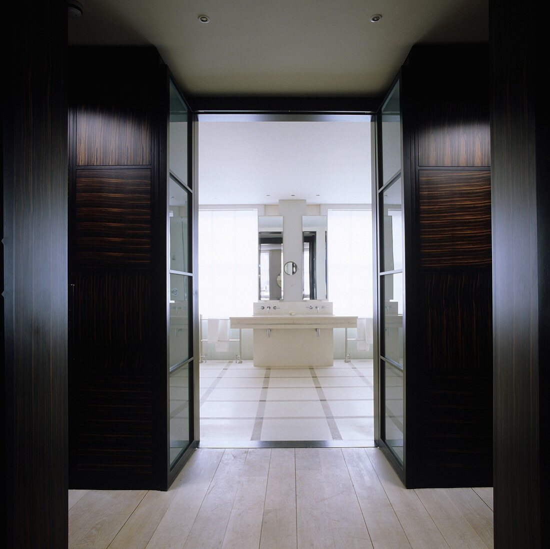 A hallway with cupboards and an open door with a view of a designer washstand