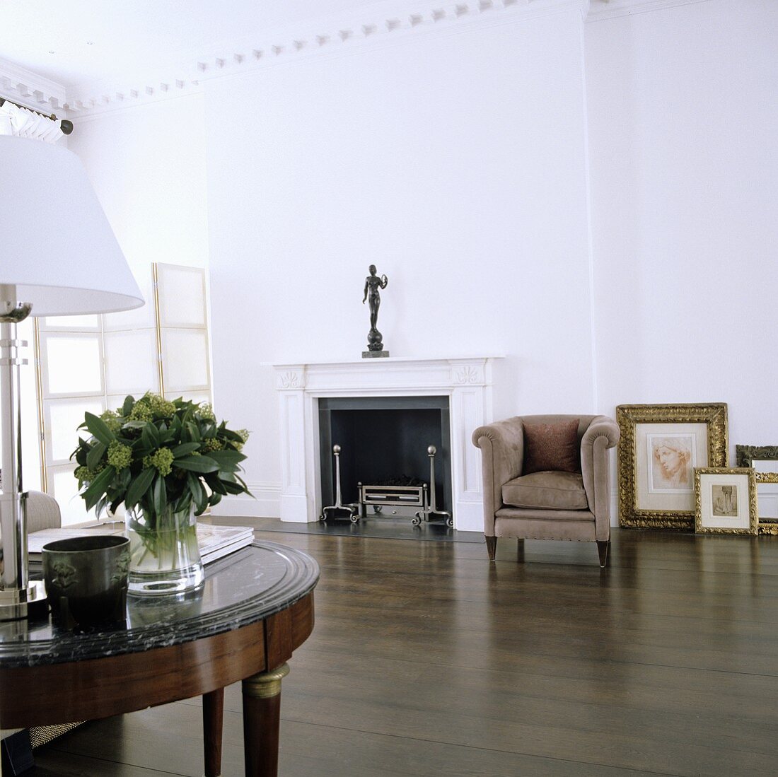 A minimalistic living room with a dark wooden floor and an armchair next to a fireplace