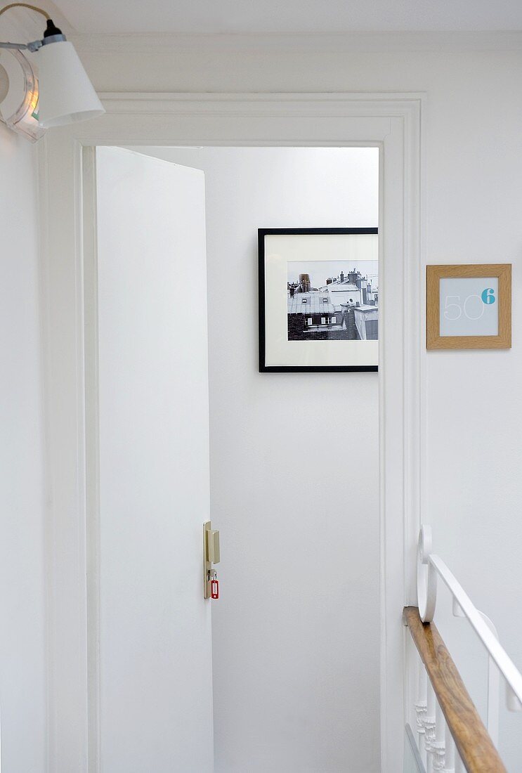 An open hotel room door with a view of a picture on the wall