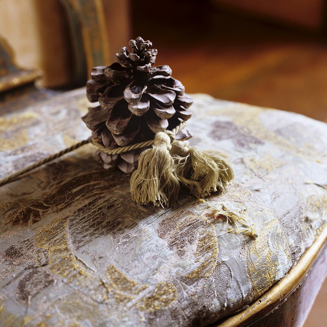 A pine cone tied with string on a worn chair