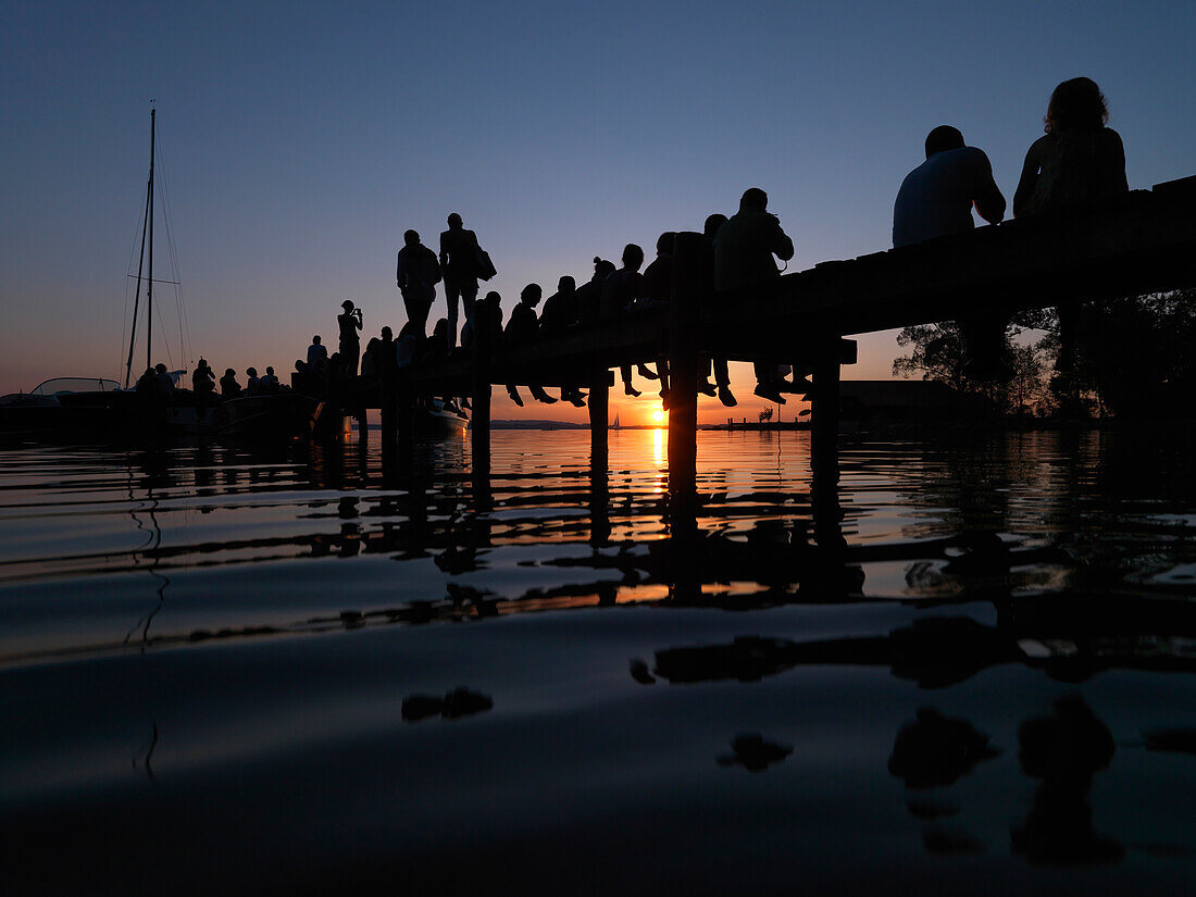 Leute auf einen Steg im Sonnenuntergang, Feldwies, Chiemsee, Bayern, Deutschland