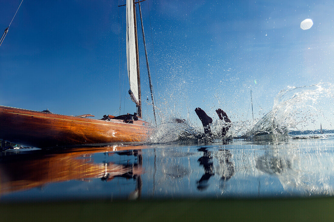 Young man jumping into water from a sailboat, Fraueninsel, lake Chiemsee, Bavaria, Germany