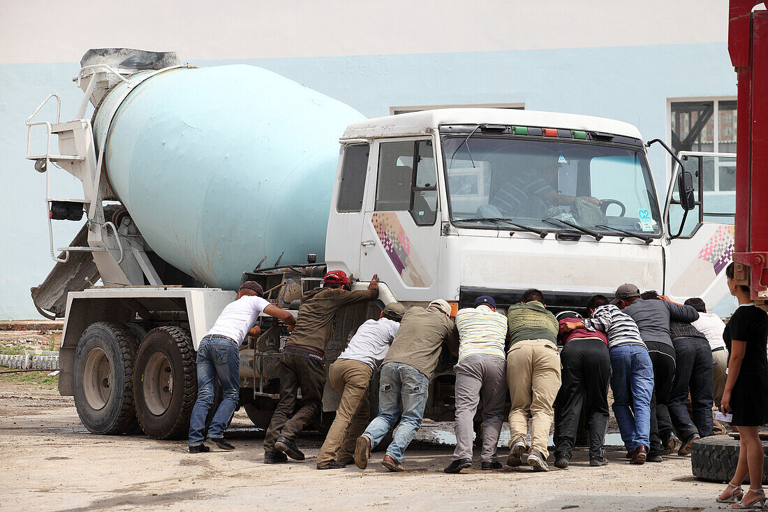 Workers pushing broken transit-truck mixer, Ulaanbaatar, Mongolia