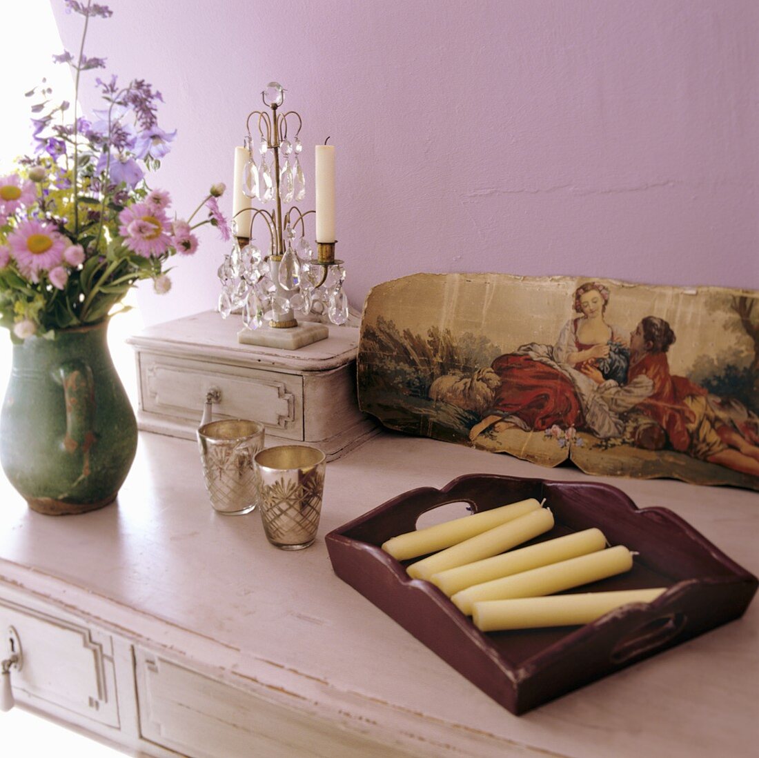 Candles, flowers and a picture on a sideboard