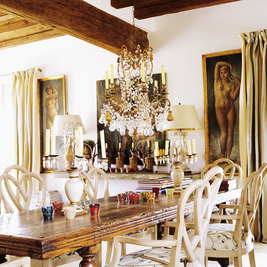 A rustic dining table with a chandelier hanging from the wood beam ceiling