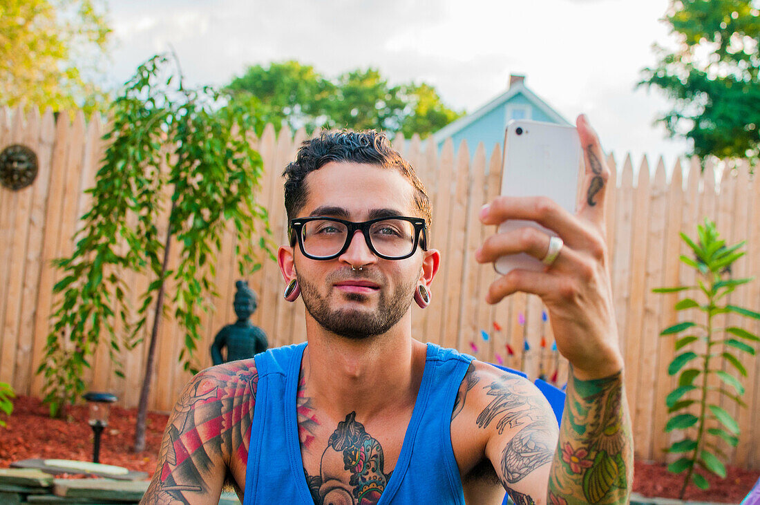 Mid adult man taking selfie on smartphone in garden