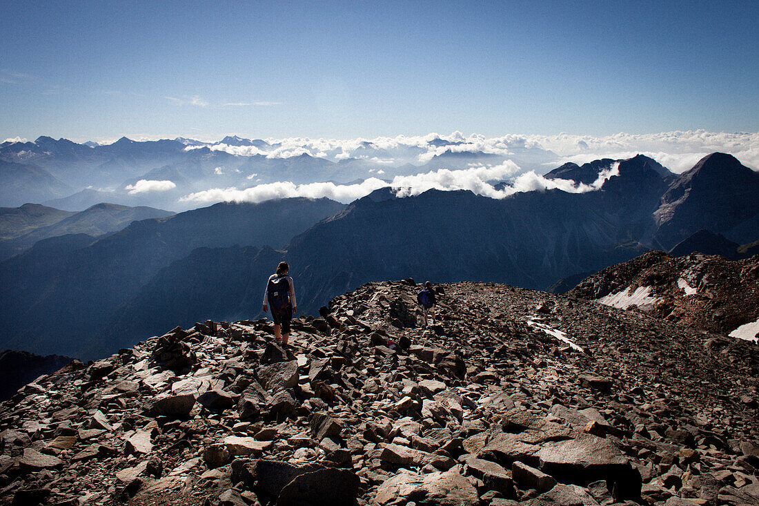 Two people hiking over boulder field, descent from Habicht (3277 m), Stubai Alps, Tyrol, Austria