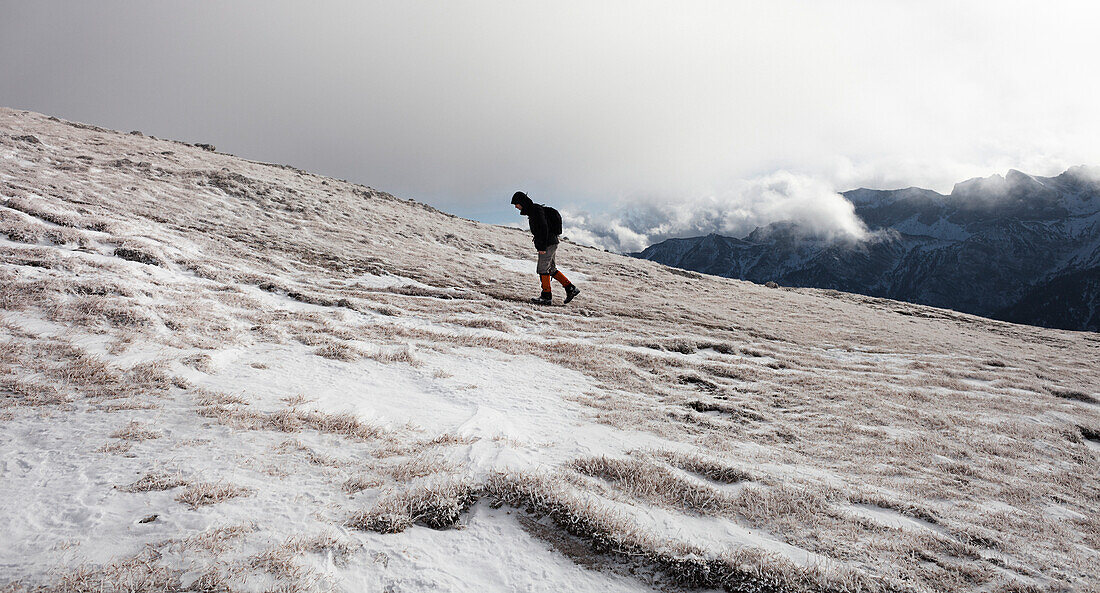 Hiker walking in snow-covered landscape, ascend to Unnutz Mountain (2078 m), Rofan Mountains, Tyrol, Austria