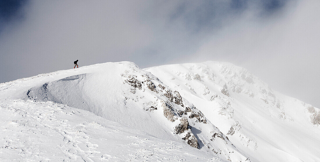Wanderer besteigt einen schneebedeckten Gipfel, Aufstieg zum Unnütz (2078 m), Rofan, Tirol, Österreich