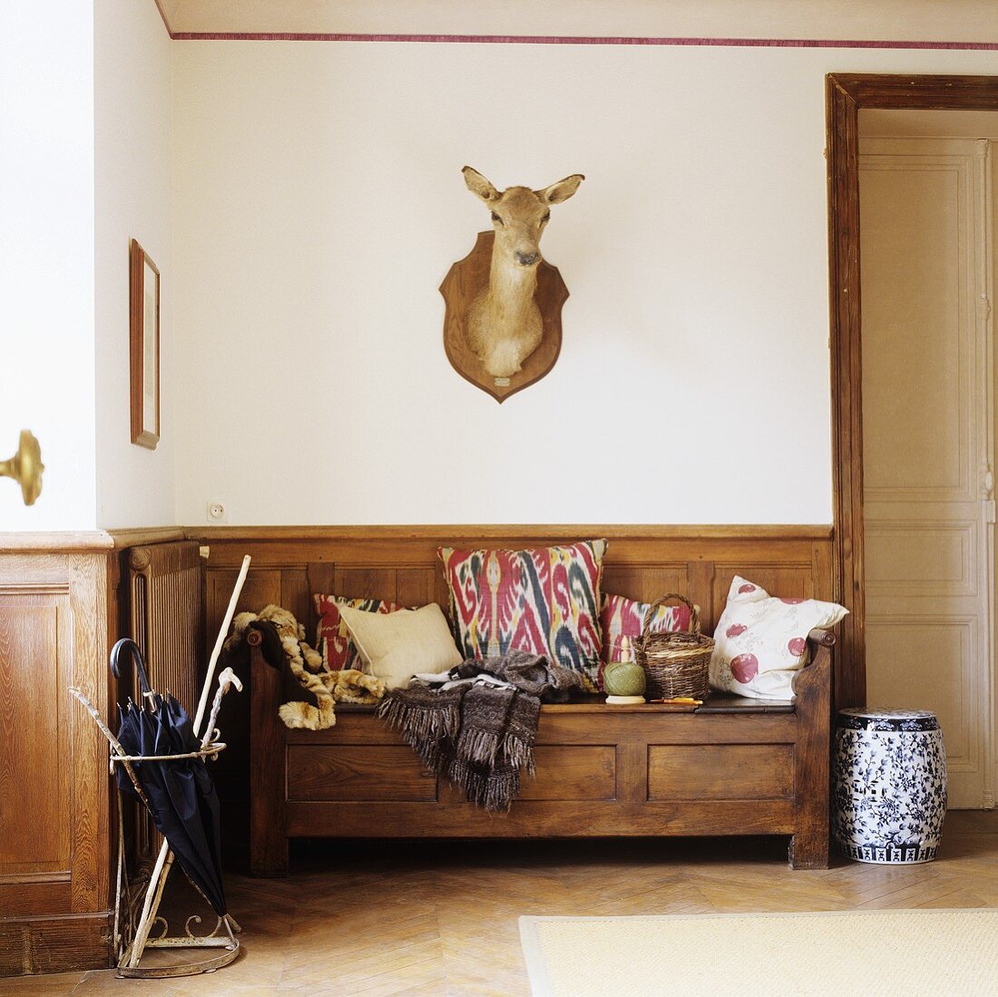 An anteroom in a country house - a wooden bench with wood panelling and an animal head on the wall