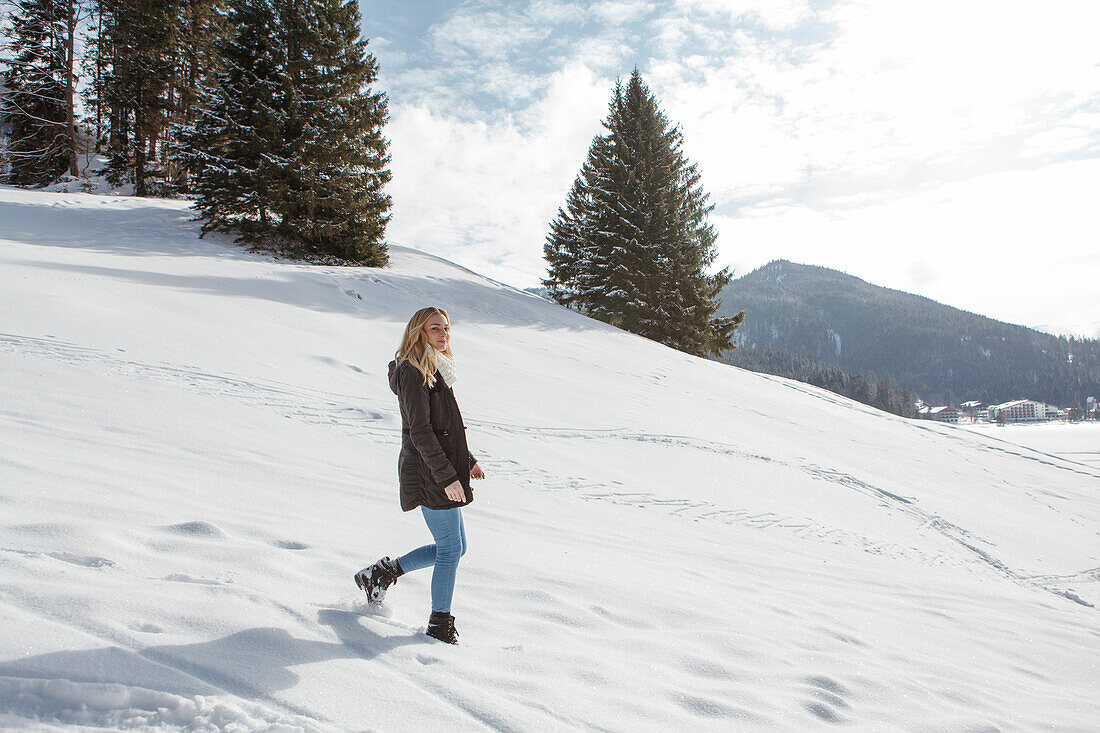 Junge Frau geht im Schnee spazieren, Spitzingsee, Oberbayern, Bayern, Deutschland