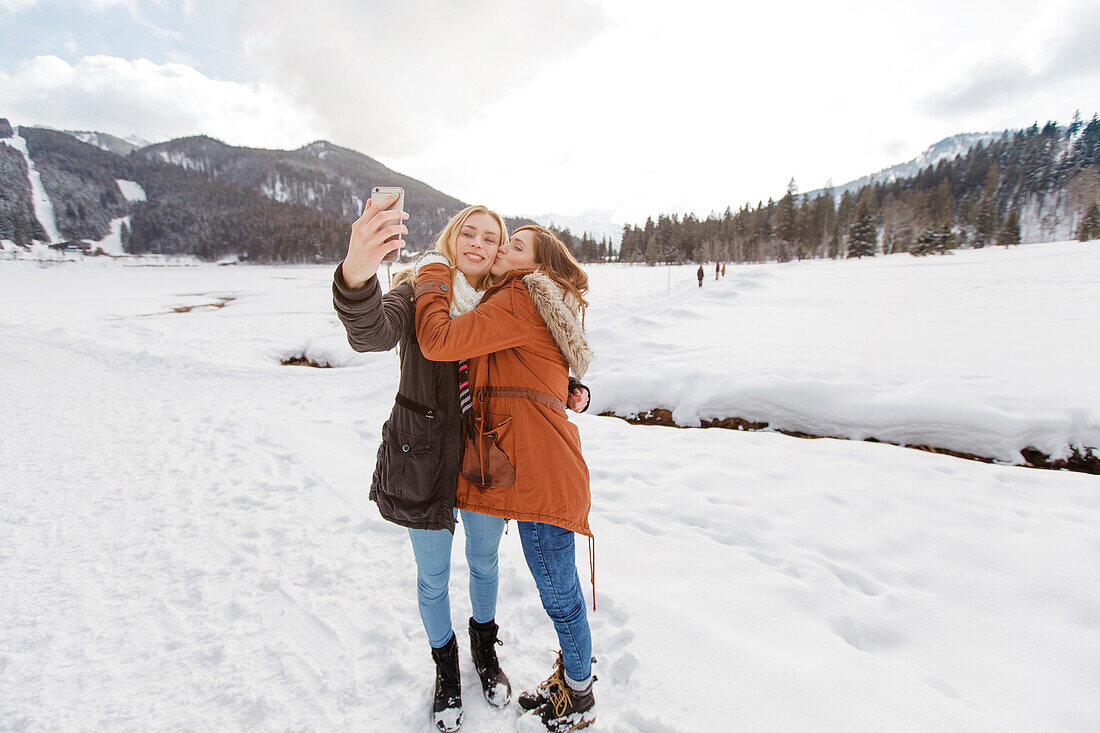 Two young women taking a selfie picture, Spitzingsee, Upper Bavaria, Germany