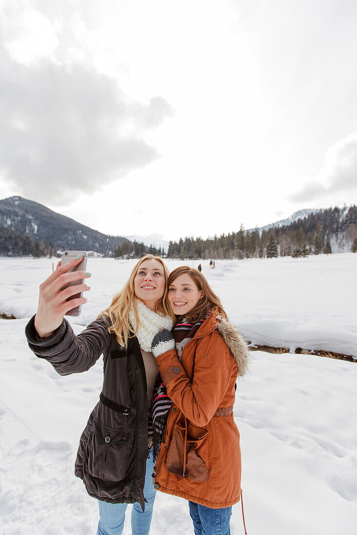 Two young women taking a selfie picture, Spitzingsee, Upper Bavaria, Germany