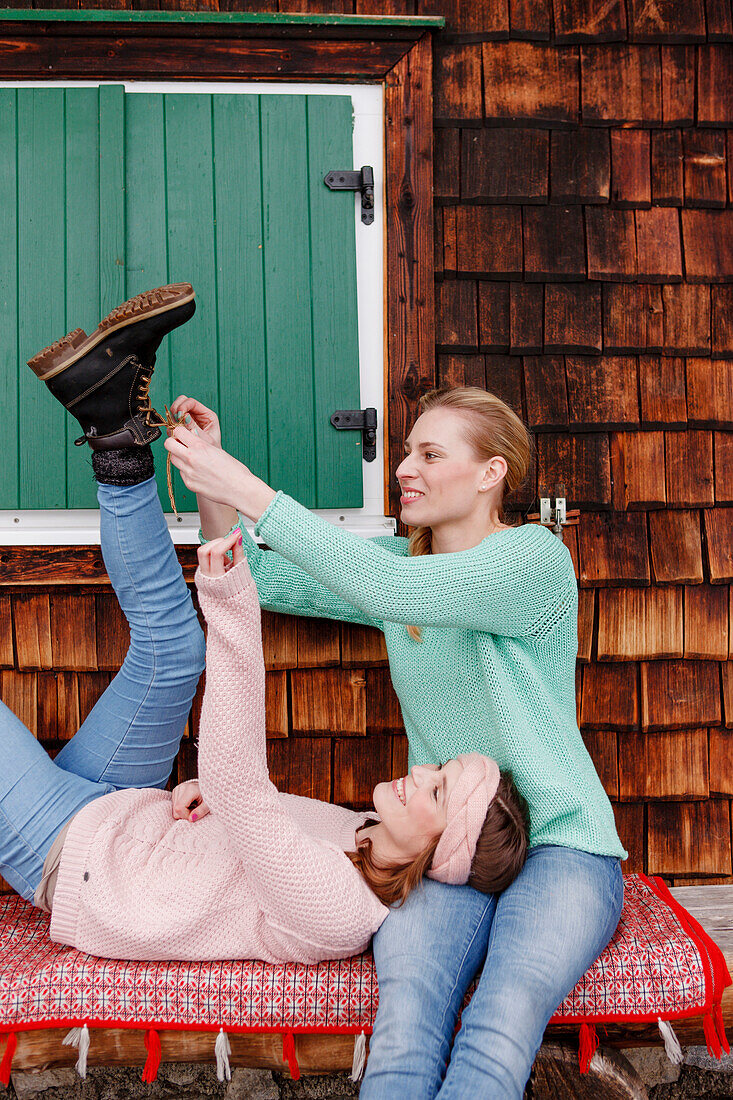 Zwei junge Frauen auf einer Bank, binden Schuh zu, Spitzingsee, Oberbayern, Bayern, Deutschland