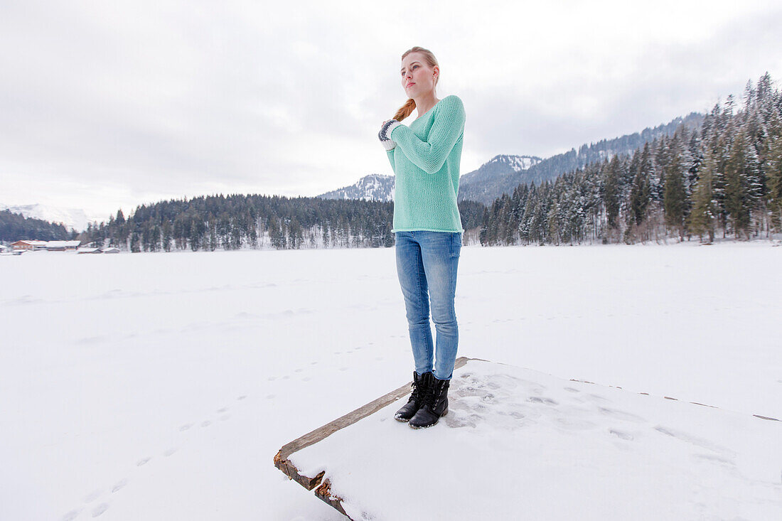 Young woman on a jetty at lake Spitzingsee, Upper Bavaria, Germany