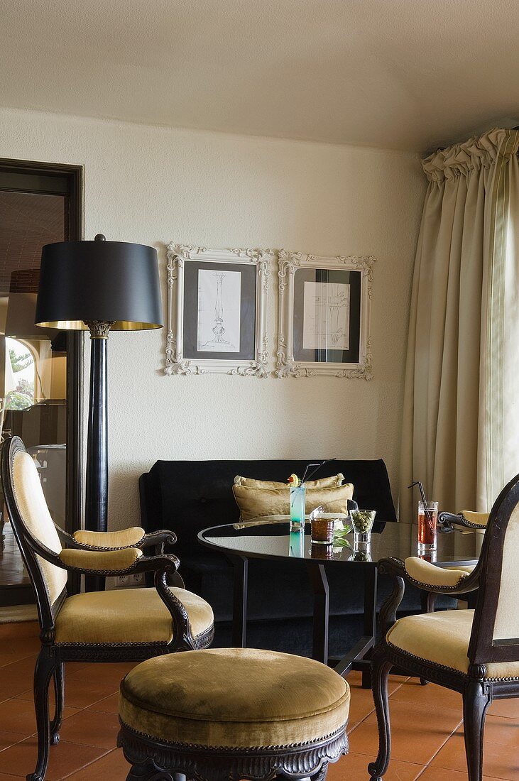 Upholstered antique chairs and a glass table in the corner of the room