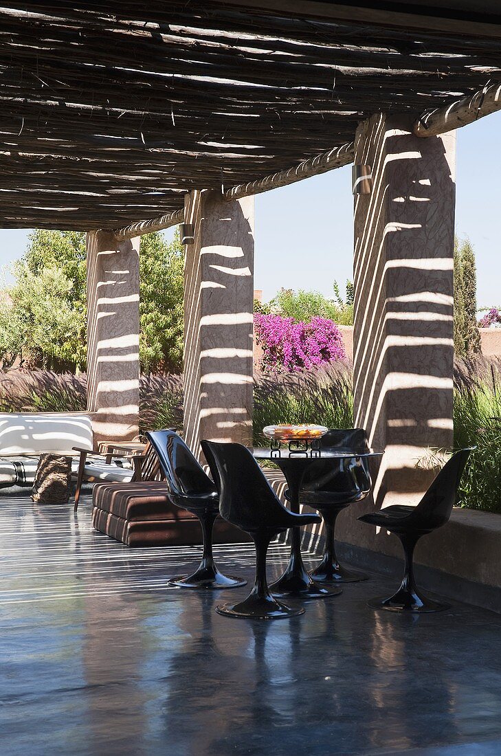 Schwarze Kunststoffstühle auf poliertem Betonboden und überdachter Terrasse in Mediterraner Landschaft