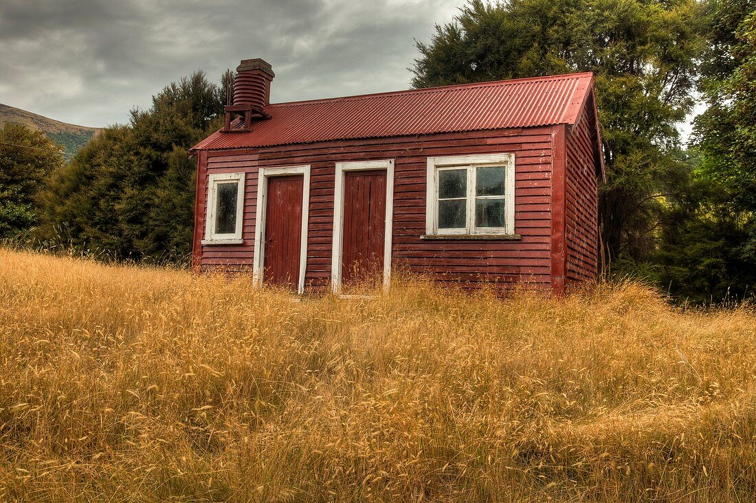 Red shed and dried grass, small farm building near Little River, Banks Peninsula, New Zealand