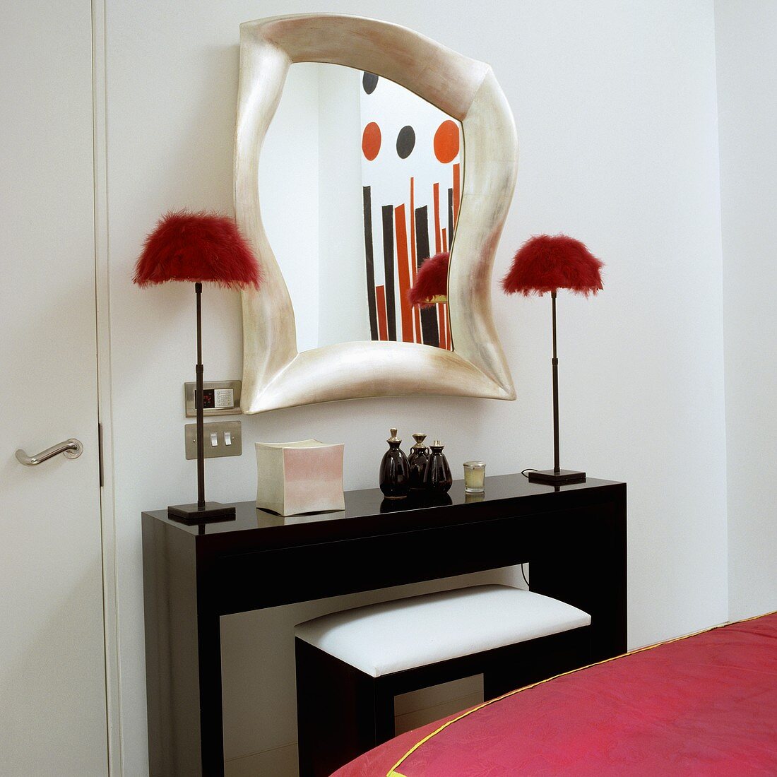 A black wall table with a mirror and table lamps in different styles