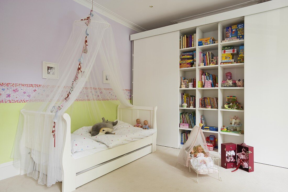 A child's bedroom - a child's bed with a canopy and a built-in shelf with sliding doors
