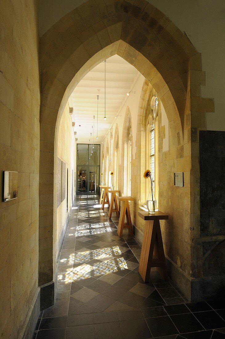 Blick durch gotischen Spitzbogen auf langgestrecktem Kirchenflur mit Bartischen