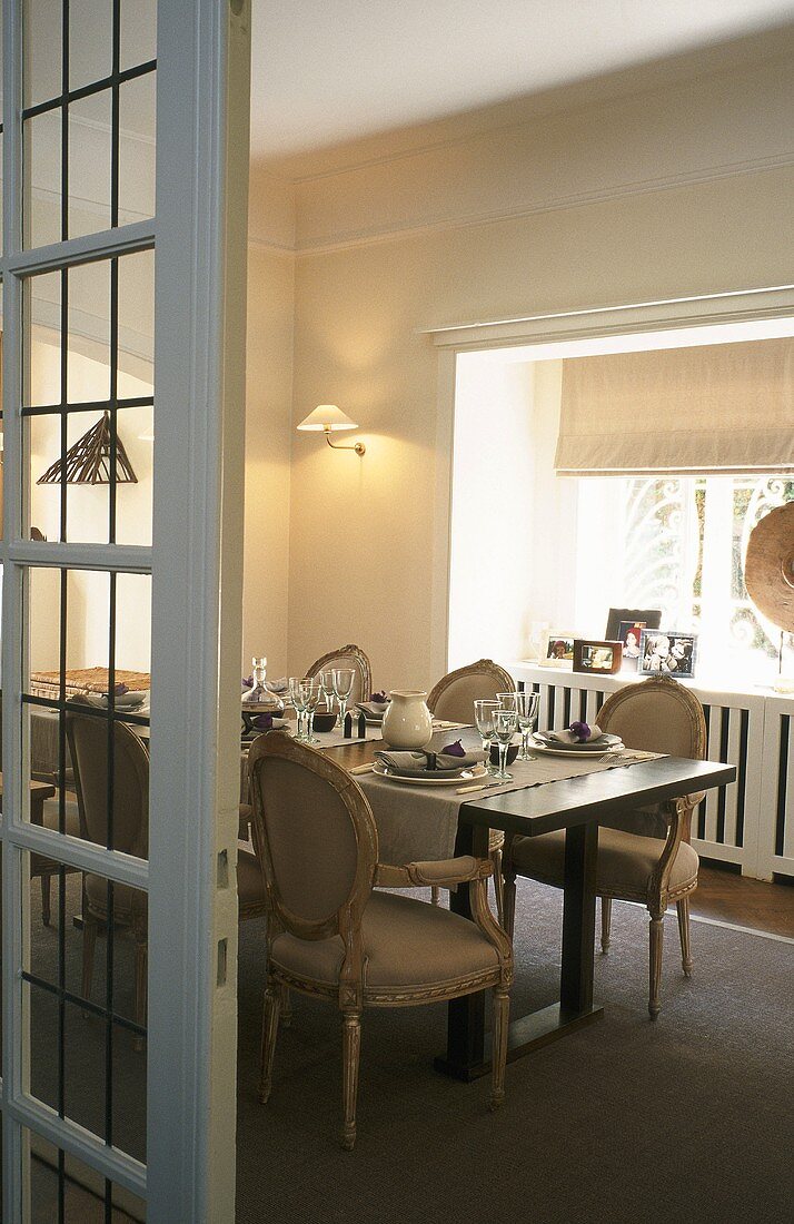 A view of a table laid in front of a window with Baroque chairs