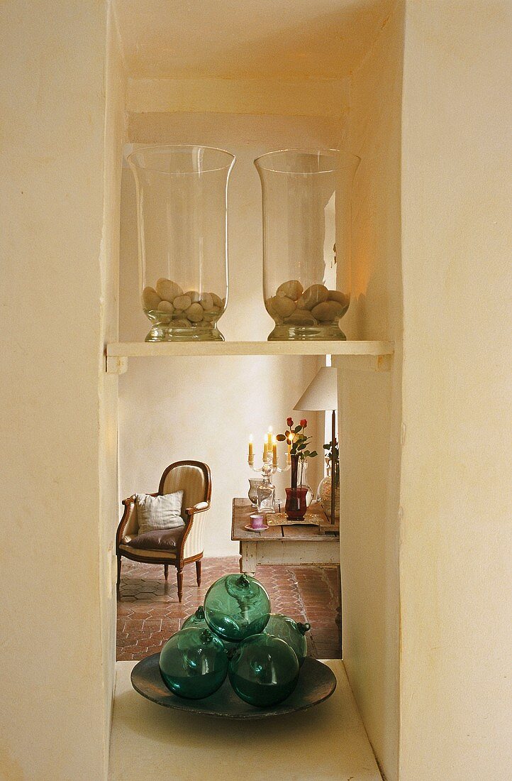 Glass jars on a shelf in a narrow niche with a view of an antique armchair