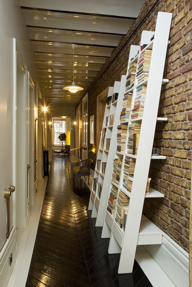 A corridor with a designer bookshelf against a brick wall