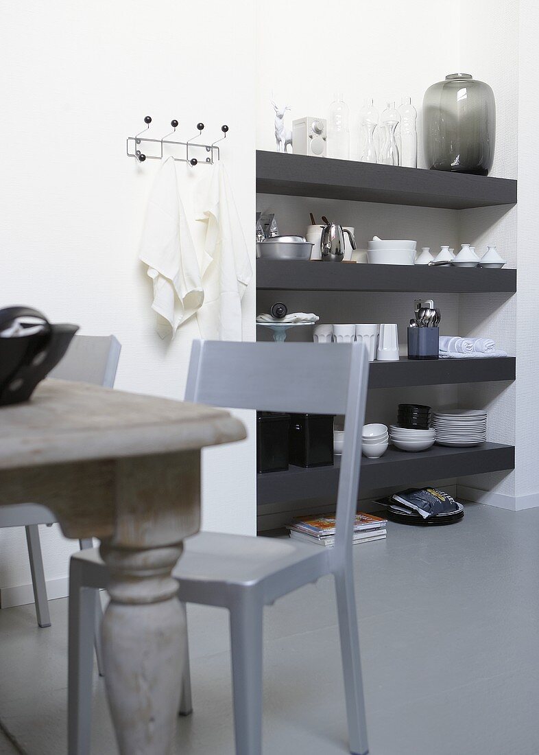 Gray wall shelves with crockery in a niche and chair on a gray floor