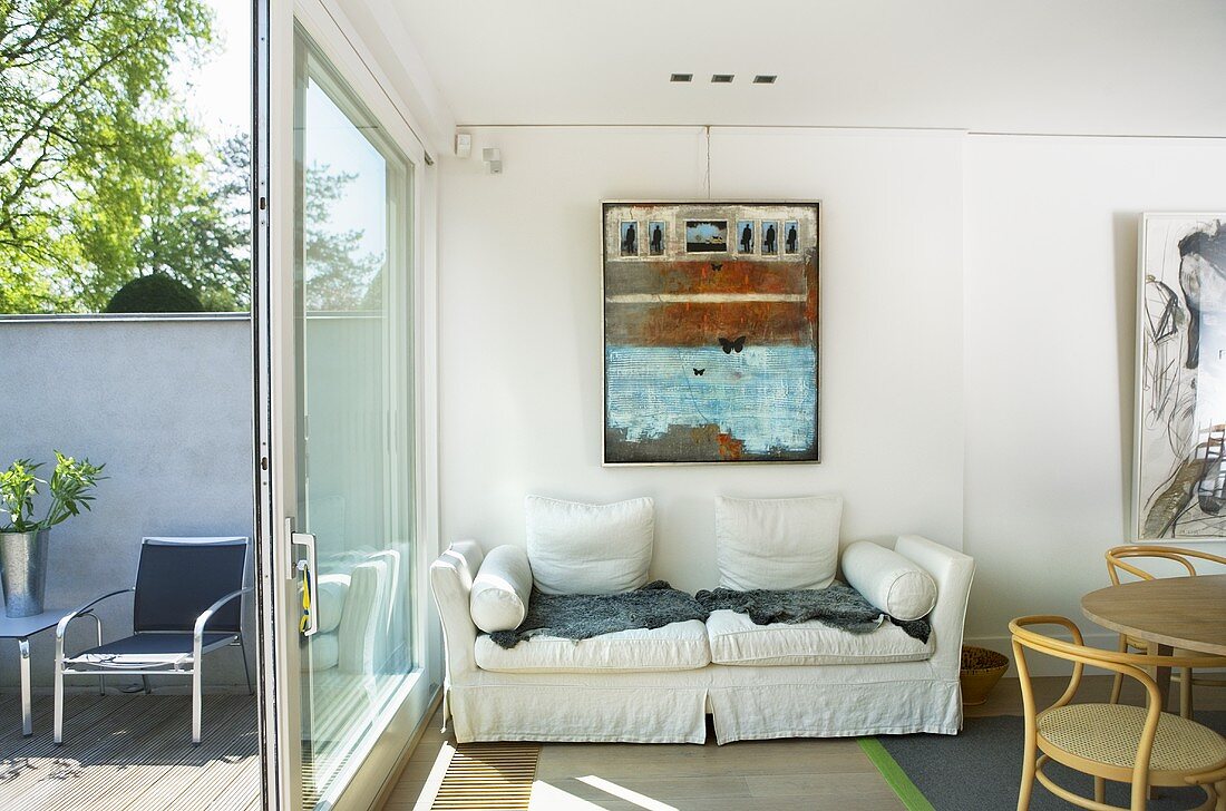 White sofa along a wall and open sliding patio door with a view of the patio